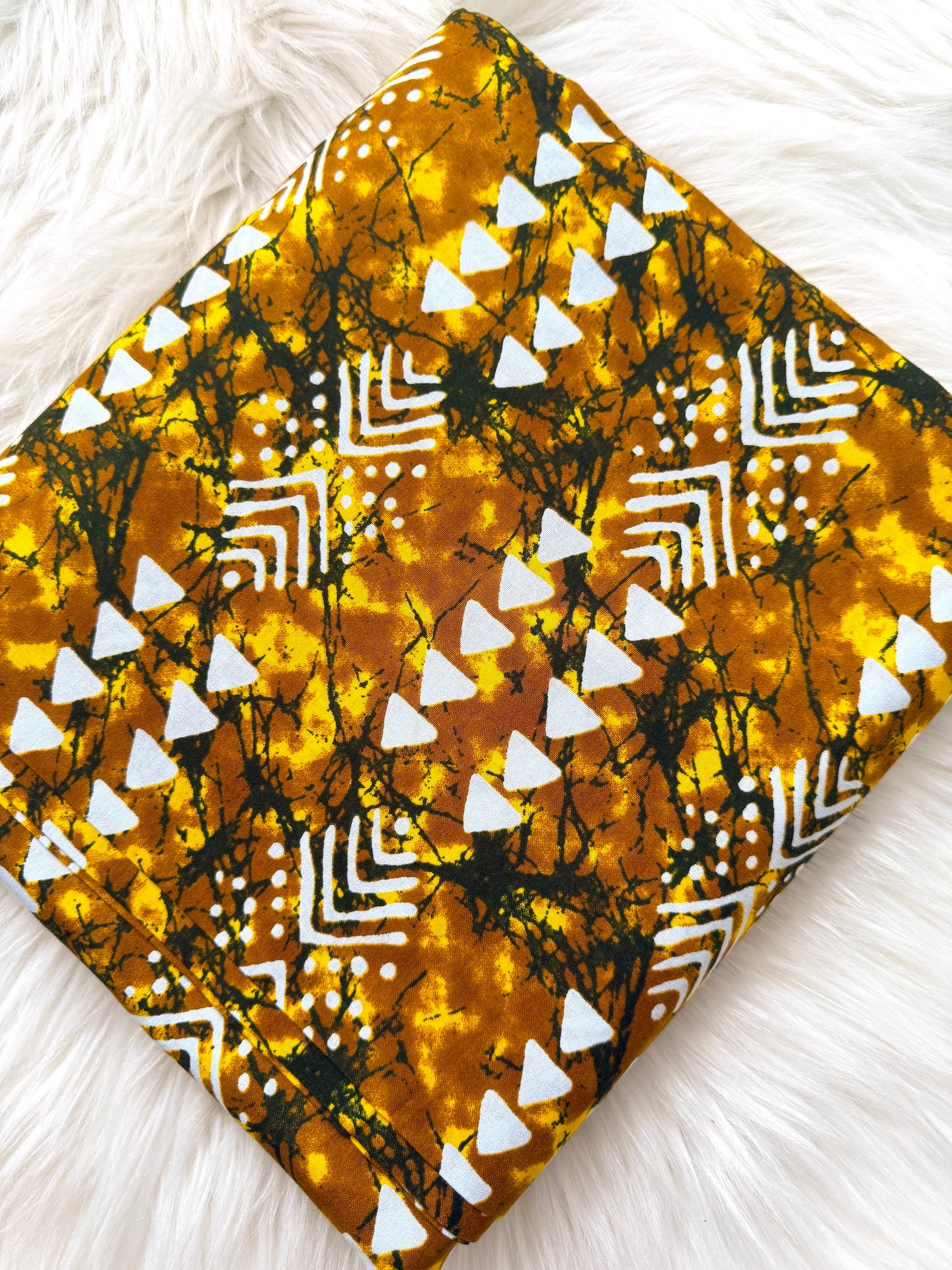 Fabric with a yellow and black pattern on a white fluffy surface