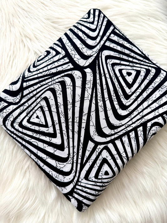 Black and white geometric patterned blanket on a white fur surface
