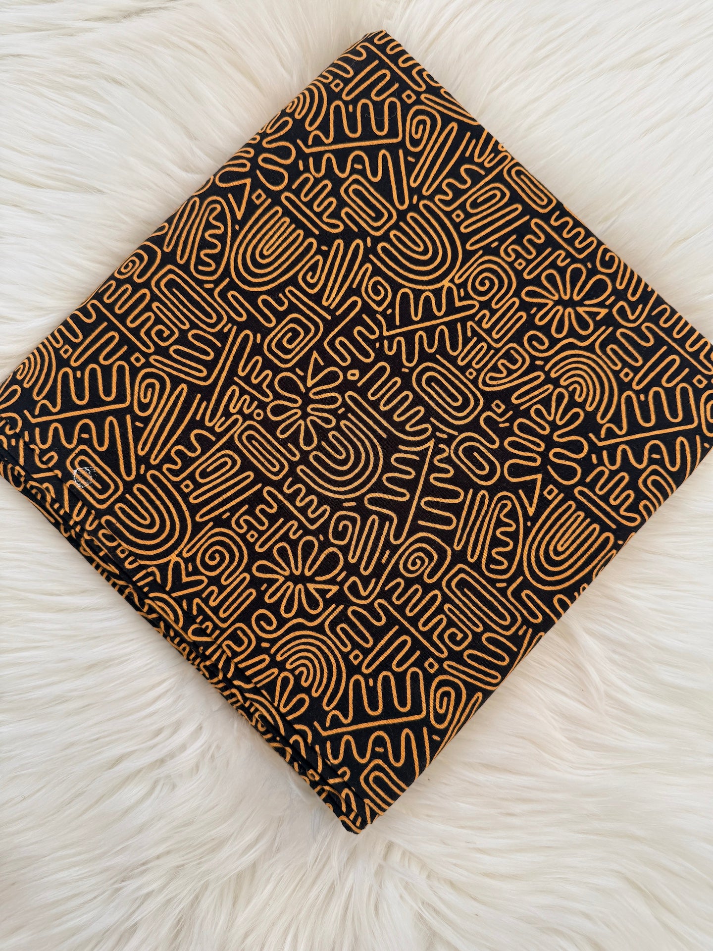 Black notebook with abstract gold pattern on a white textured surface