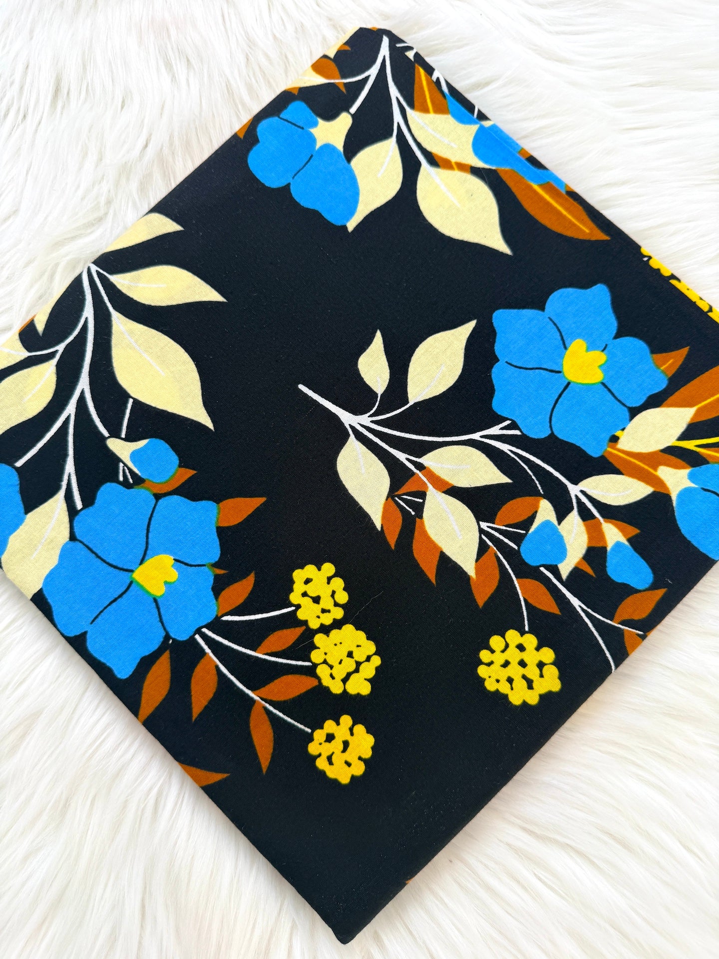 Floral patterned fabric with blue, yellow, and orange flowers on a black background.