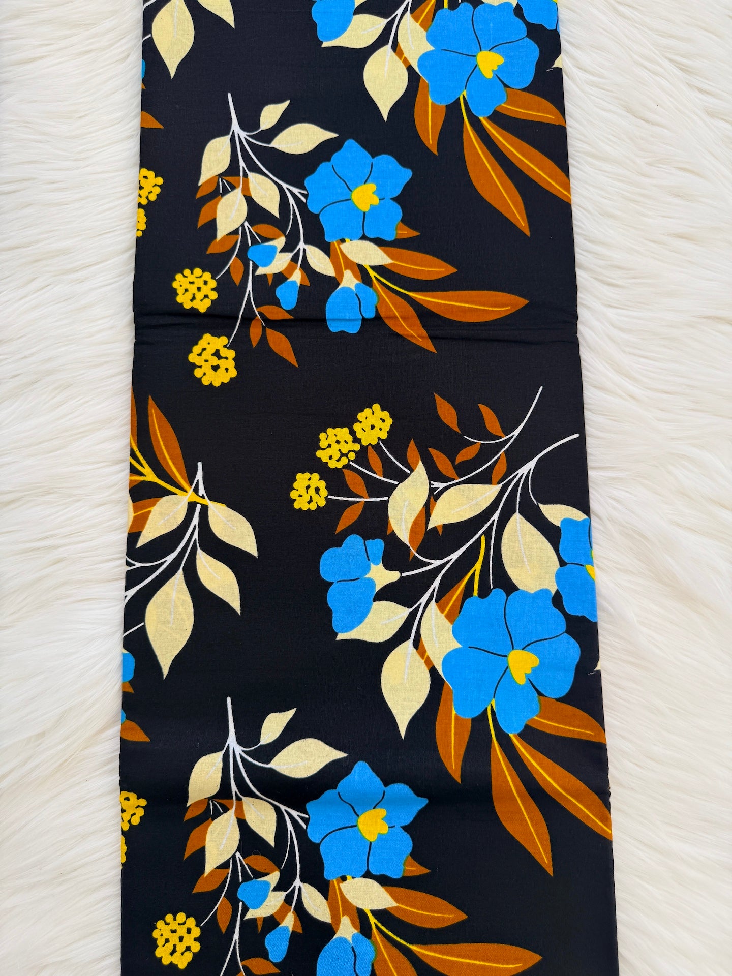 Floral patterned fabric with blue, yellow, and orange flowers on a black background.