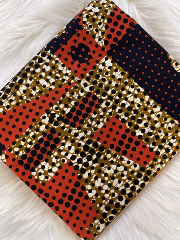 Patterned fabric with red, black, and gold colors on a white textured surface