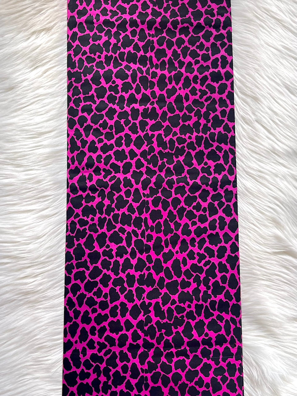 Phone case with pink and black leopard print pattern on a white fur background