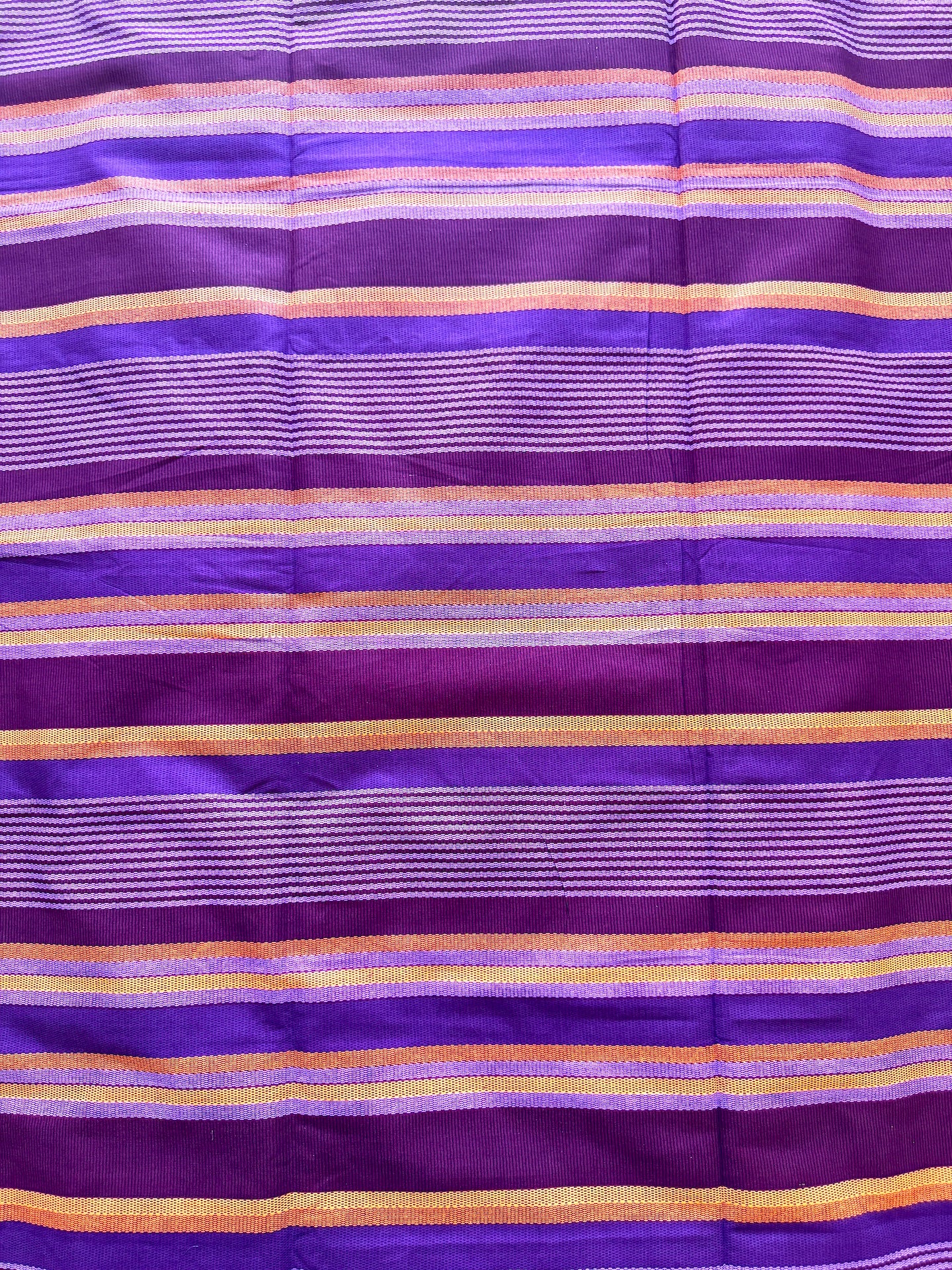 A close-up of a purple striped fabric with horizontal bands of lighter lavender, white, and orange-gold.