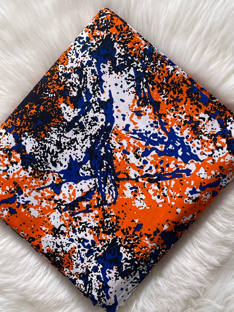 Fabric with orange, blue, and white abstract pattern on a white surface