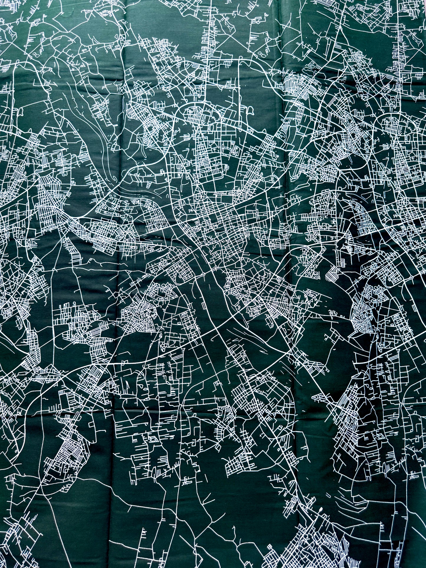 A dark green map print featuring intricate white street lines and city layout details, shown flat and filling the frame.