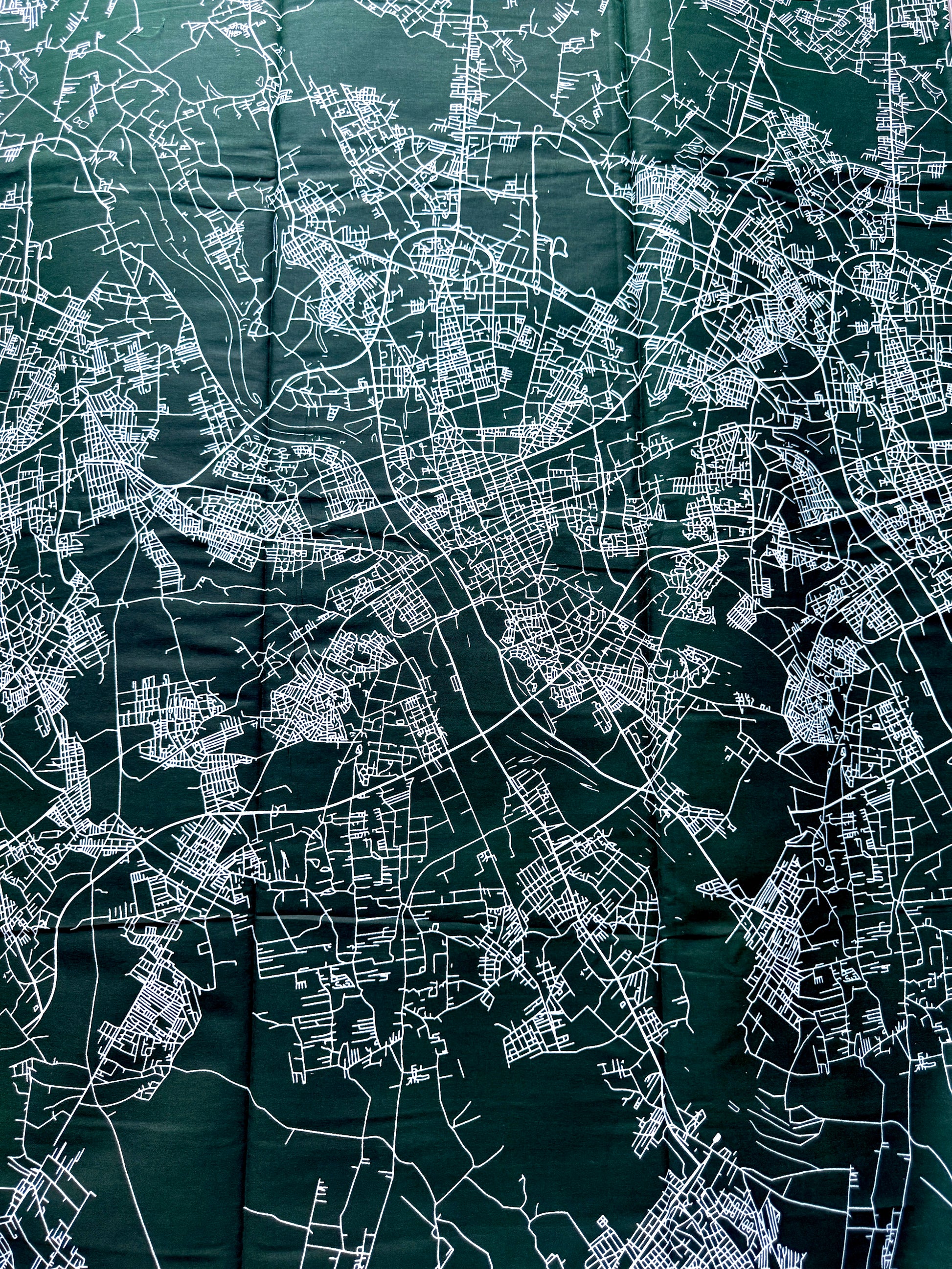 A dark green map print featuring intricate white street lines and city layout details, shown flat and filling the frame.