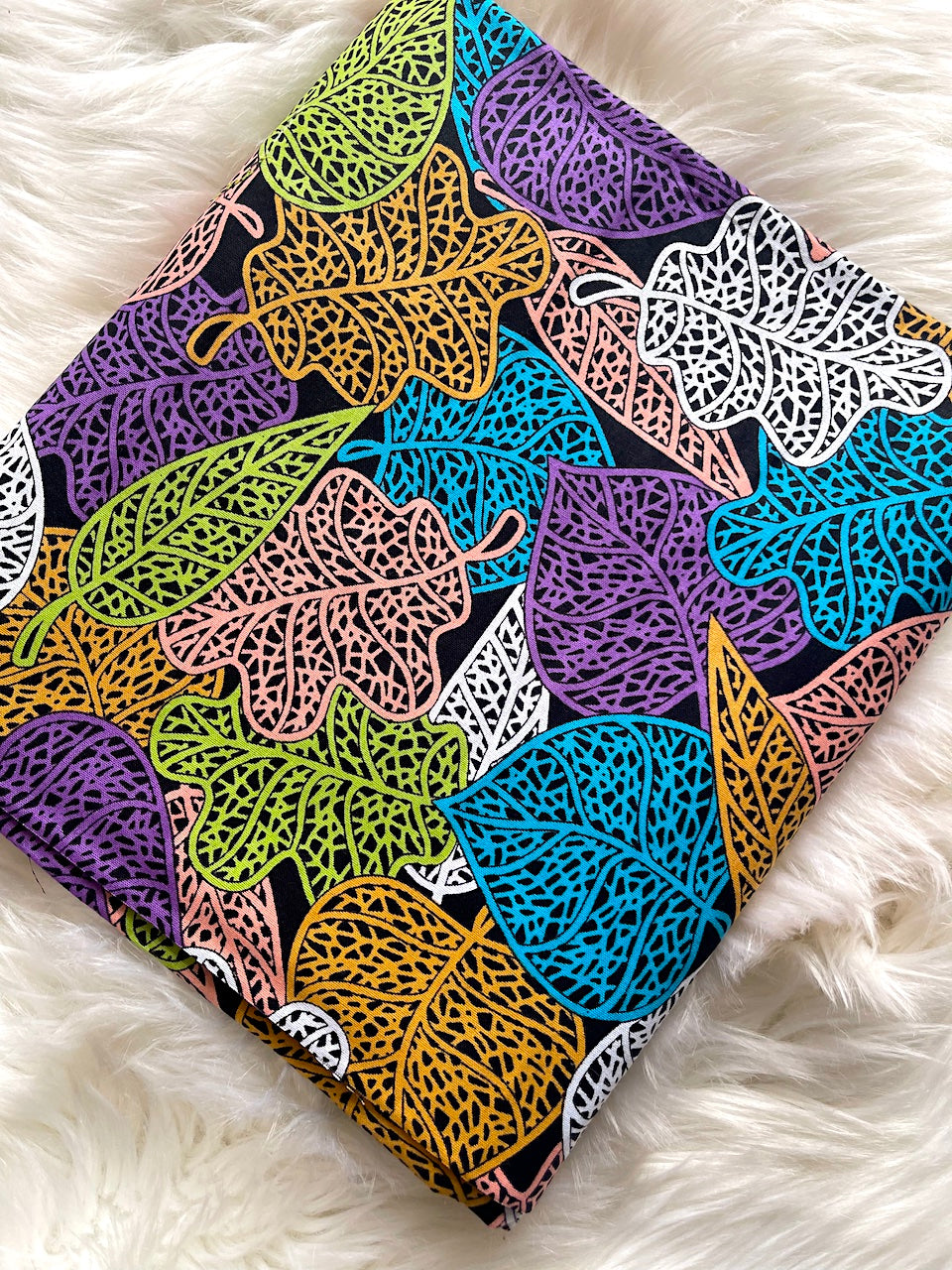Colorful leaf-patterned fabric on a white fluffy surface