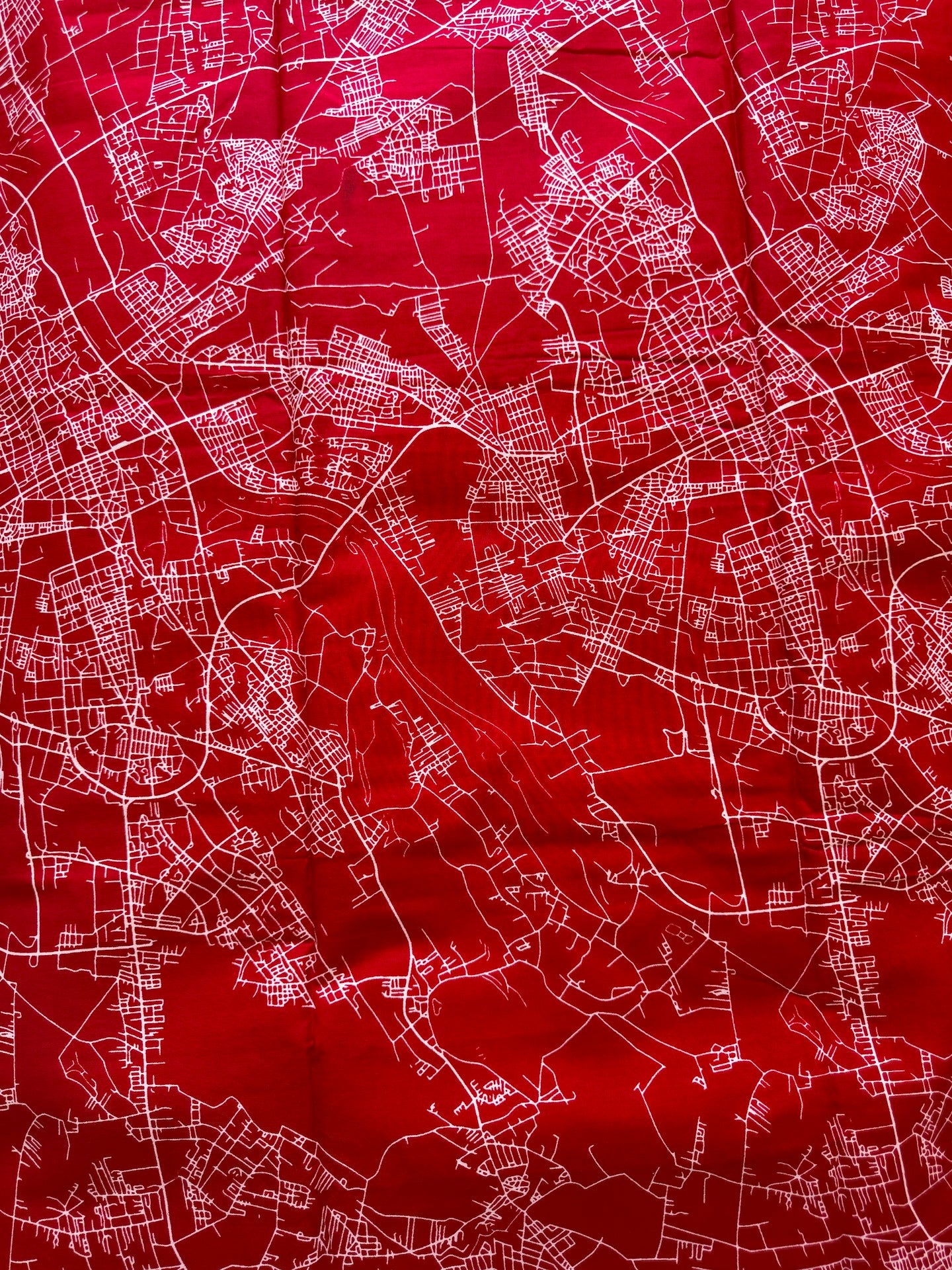 A red fabric print featuring a white street map pattern, shown as a close-up of the textile surface.