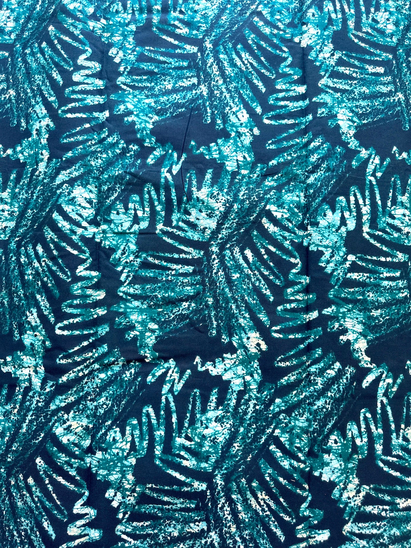 A close-up of a textured fabric or wallpaper pattern featuring abstract, leaf-like or fern-like shapes in bright teal, aqua, and white on a dark navy background.