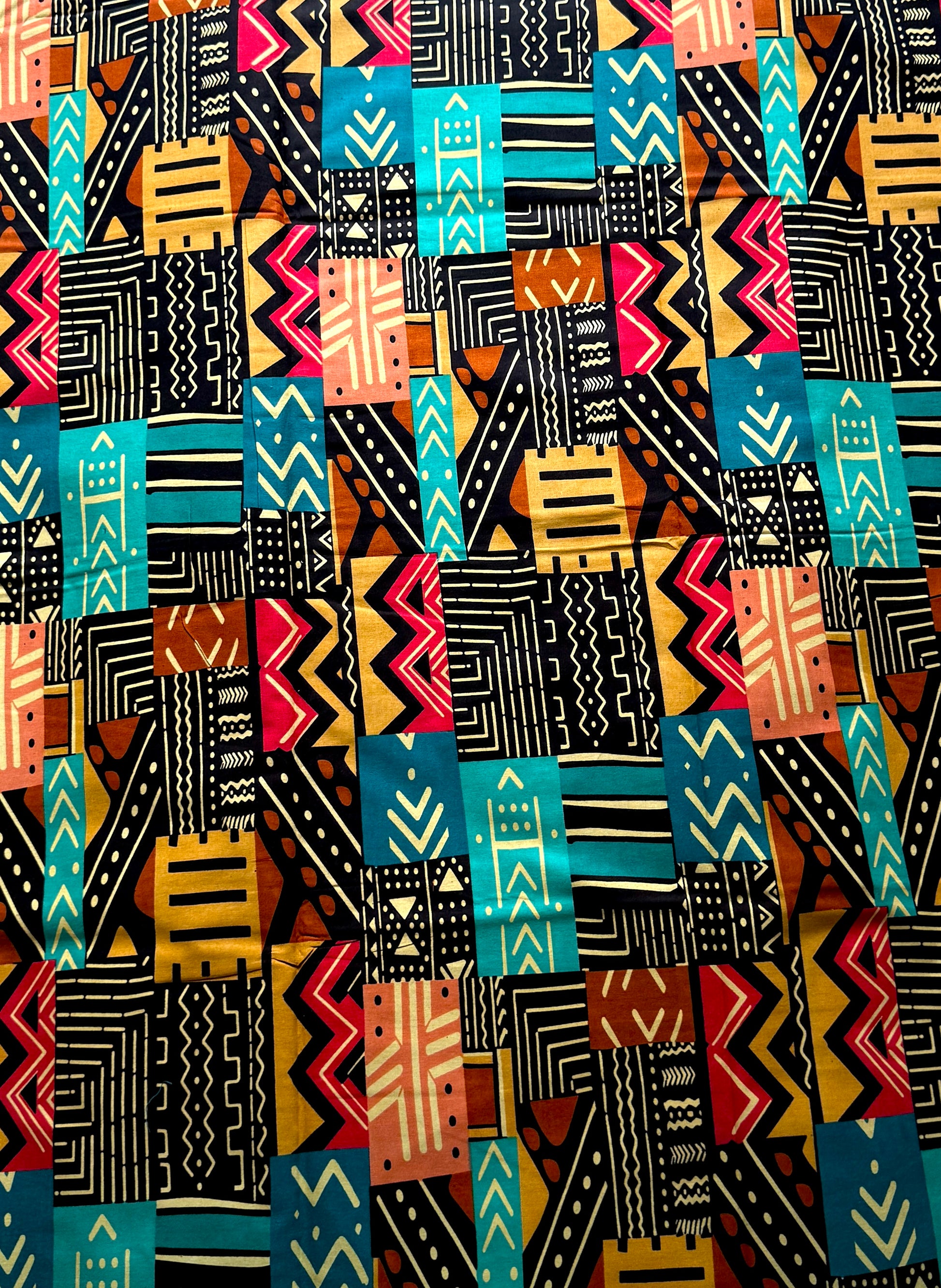 A close-up of a colorful geometric patterned fabric with vertical and horizontal tribal-style blocks in black, orange, turquoise, red, yellow, and cream.