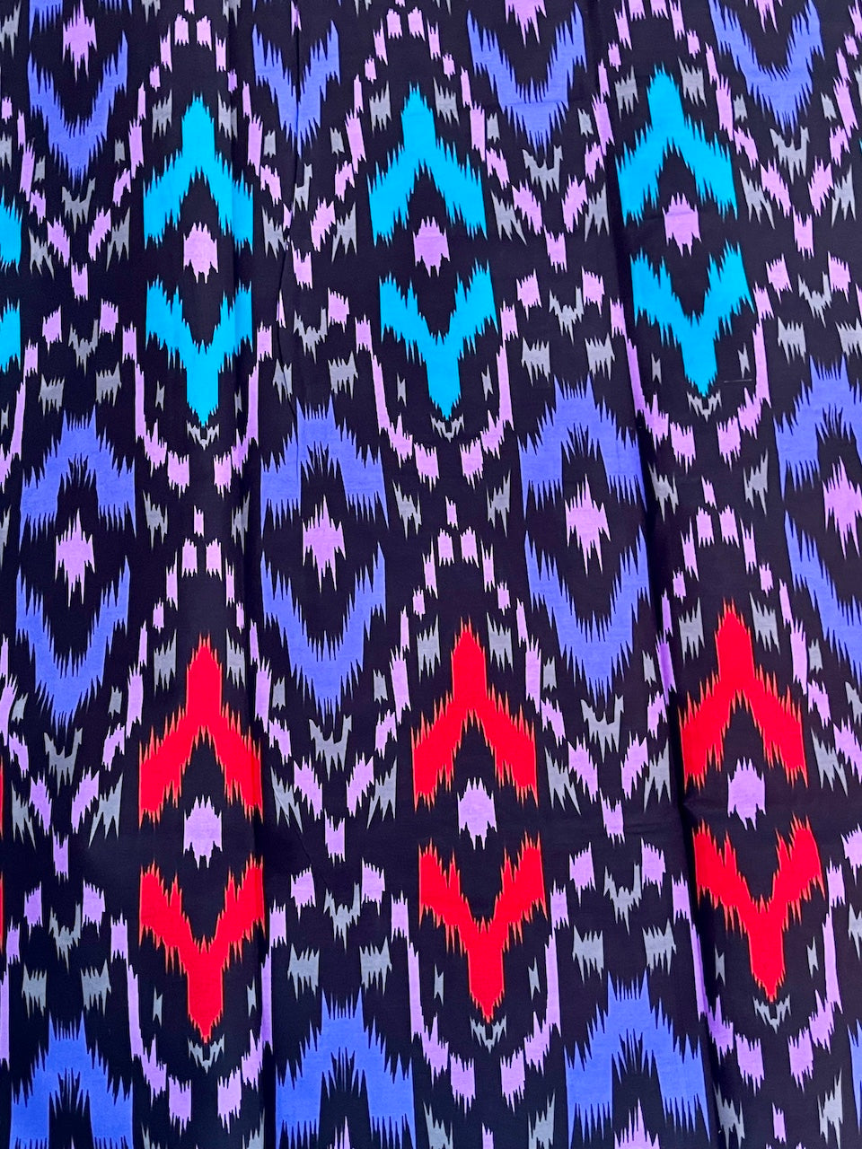 Patterned fabric with blue, red, and purple colors on a dark background
