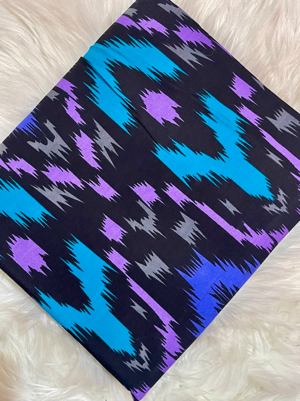 Fabric with blue, purple, and gray geometric pattern on a white surface