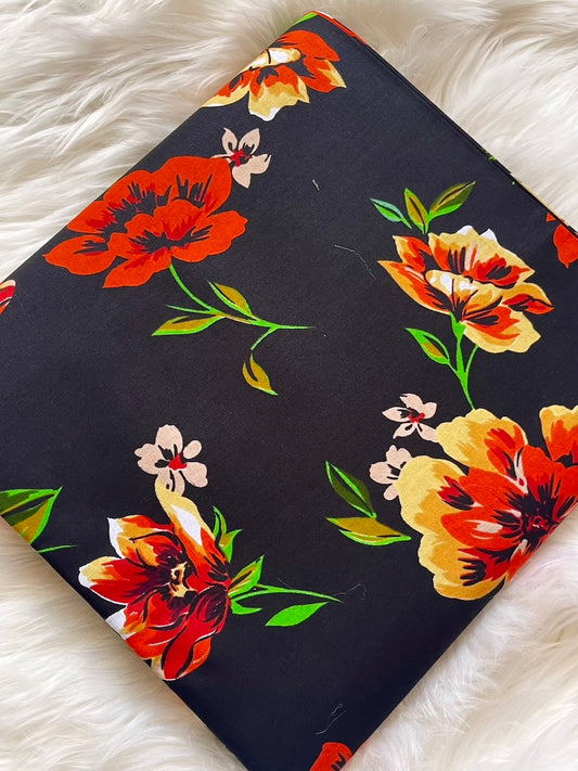 Floral-patterned fabric with red, orange, and yellow flowers on a black background, laid flat on a white surface.