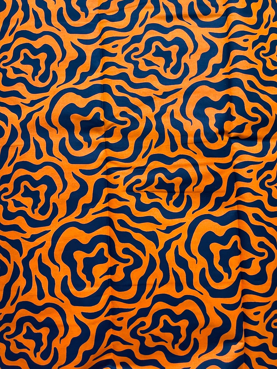 Pattern of wavy lines in orange and blue on a textured fabric background