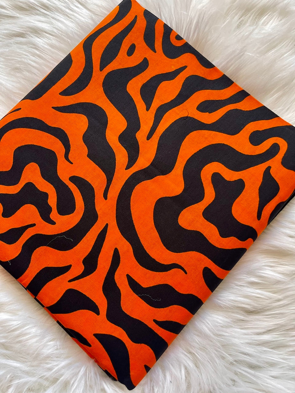 Orange and black zebra patterned fabric on a white fur background