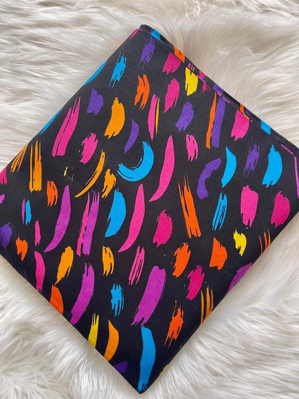 Colorful abstract pattern on a black background on a white fluffy surface