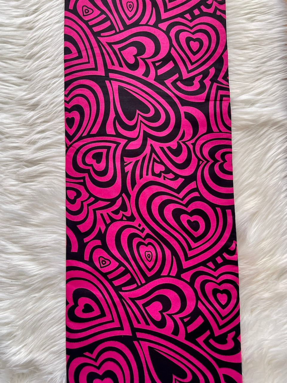 Yoga mat with pink and black heart pattern on a white fluffy surface
