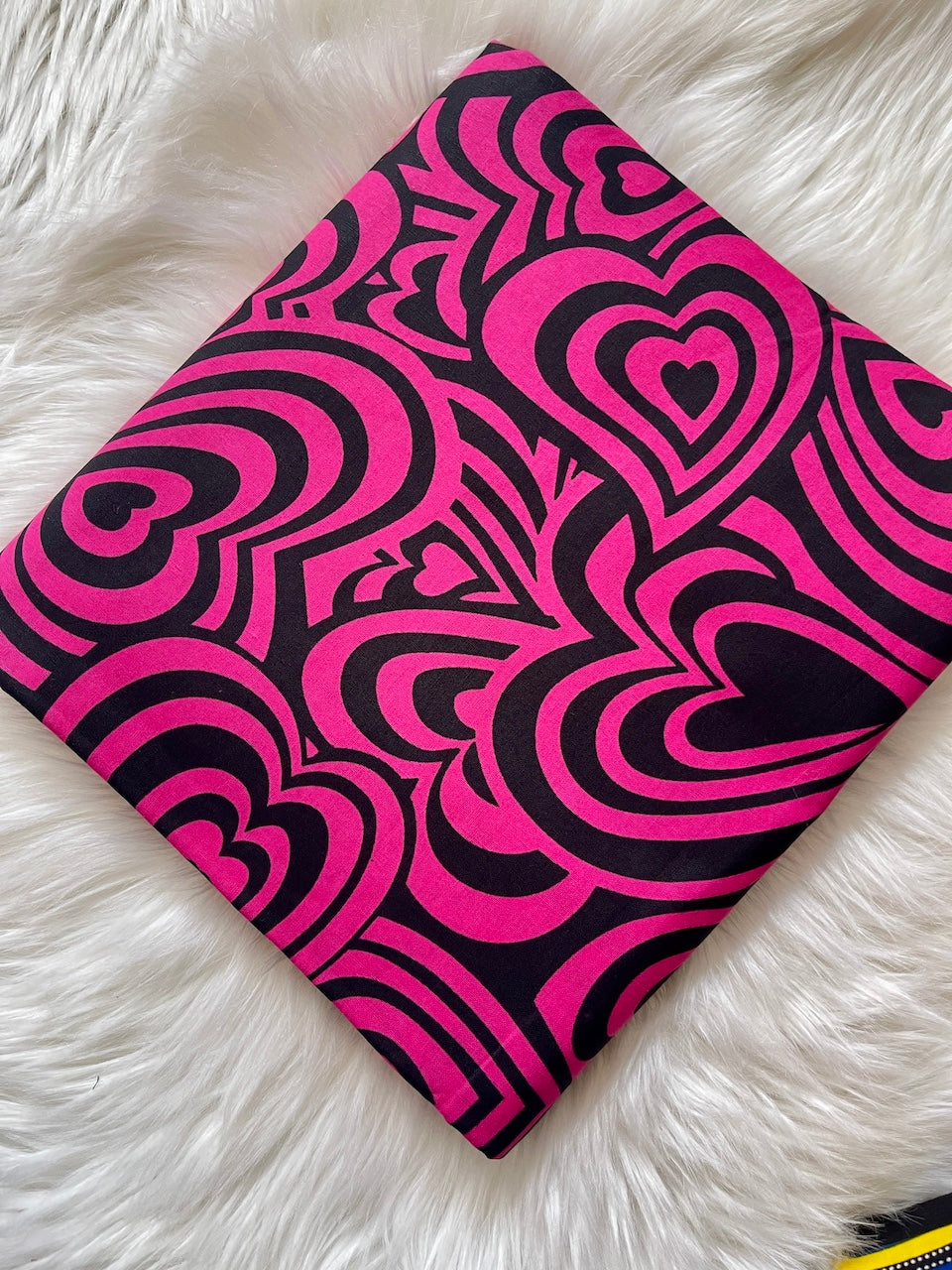 Pink and black heart-patterned notebook on a white furry surface