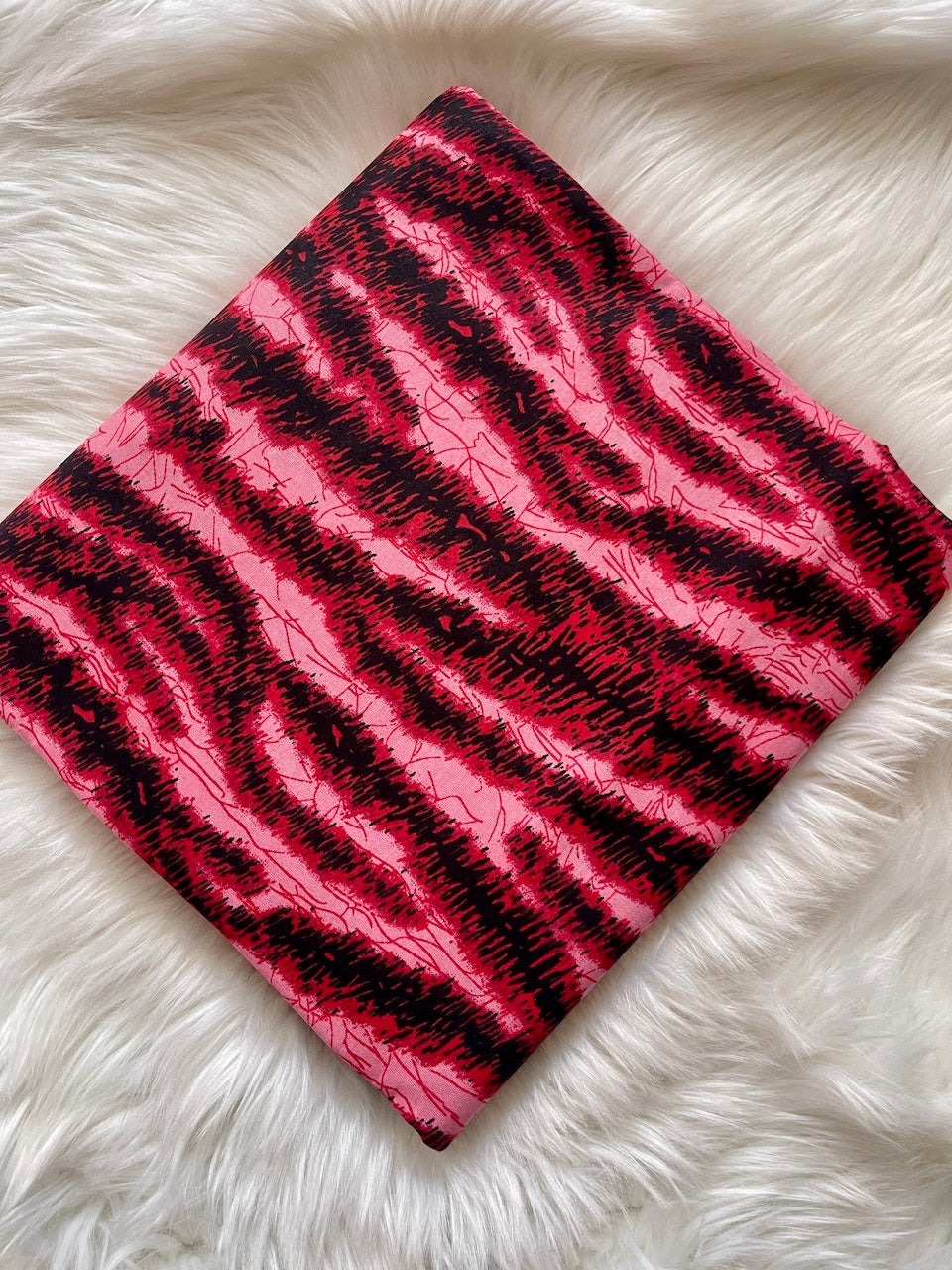 Pink and black striped fabric on a white furry surface