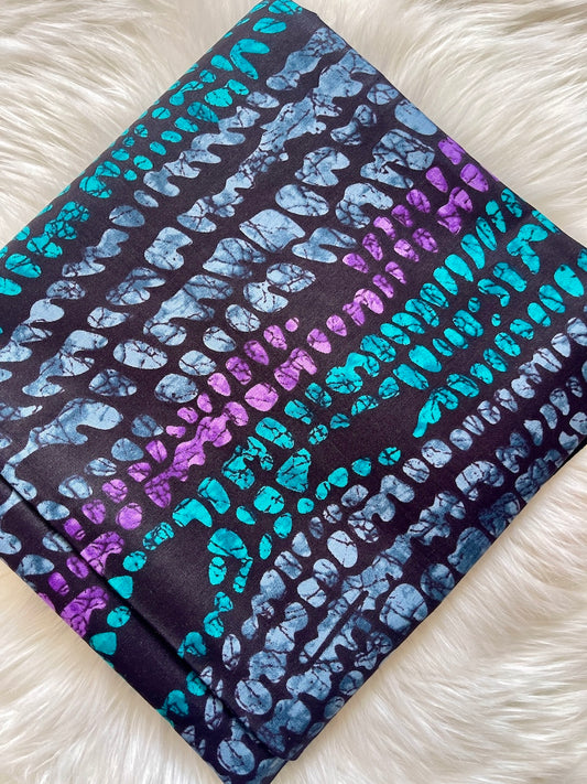 Folded fabric with blue and purple abstract pattern on a white fluffy surface