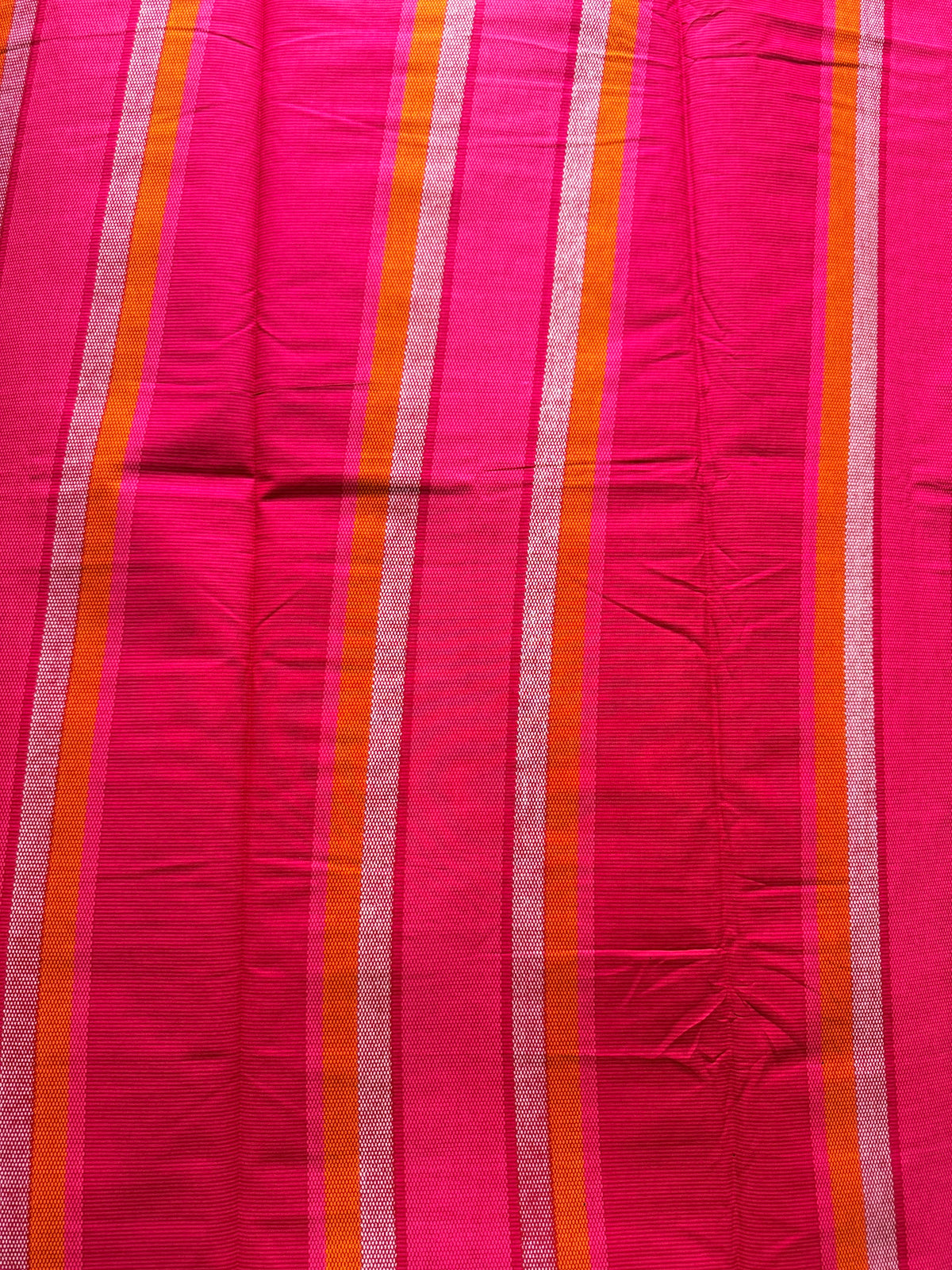 A close-up of a bright pink fabric with vertical stripes in orange, white, and a darker pink.