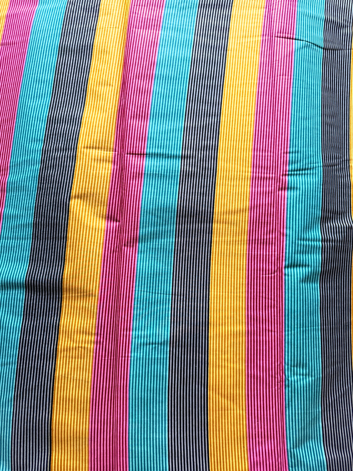 A close-up of a striped fabric with vertical bands of turquoise blue, magenta pink, mustard yellow, and black with thin white pinstripes.