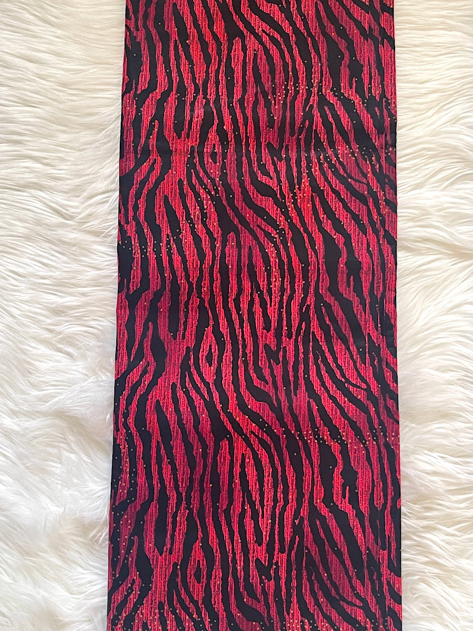 Red and black zebra patterned fabric on a white fur background