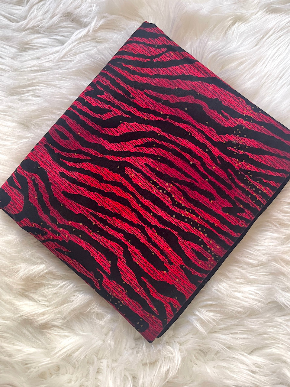 Red and black zebra patterned notebook on a white fluffy surface