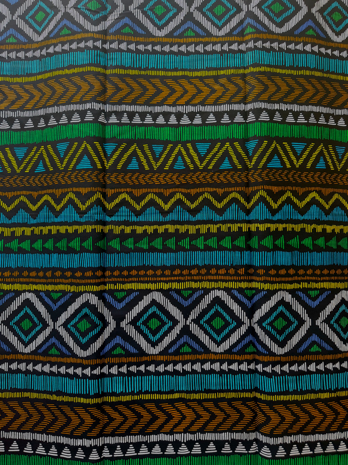 A close-up of a woven textile with horizontal bands of geometric patterns in green, blue, yellow, brown, black, and white.