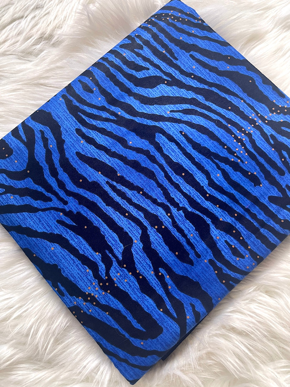Blue and black zebra patterned fabric on a white fluffy surface