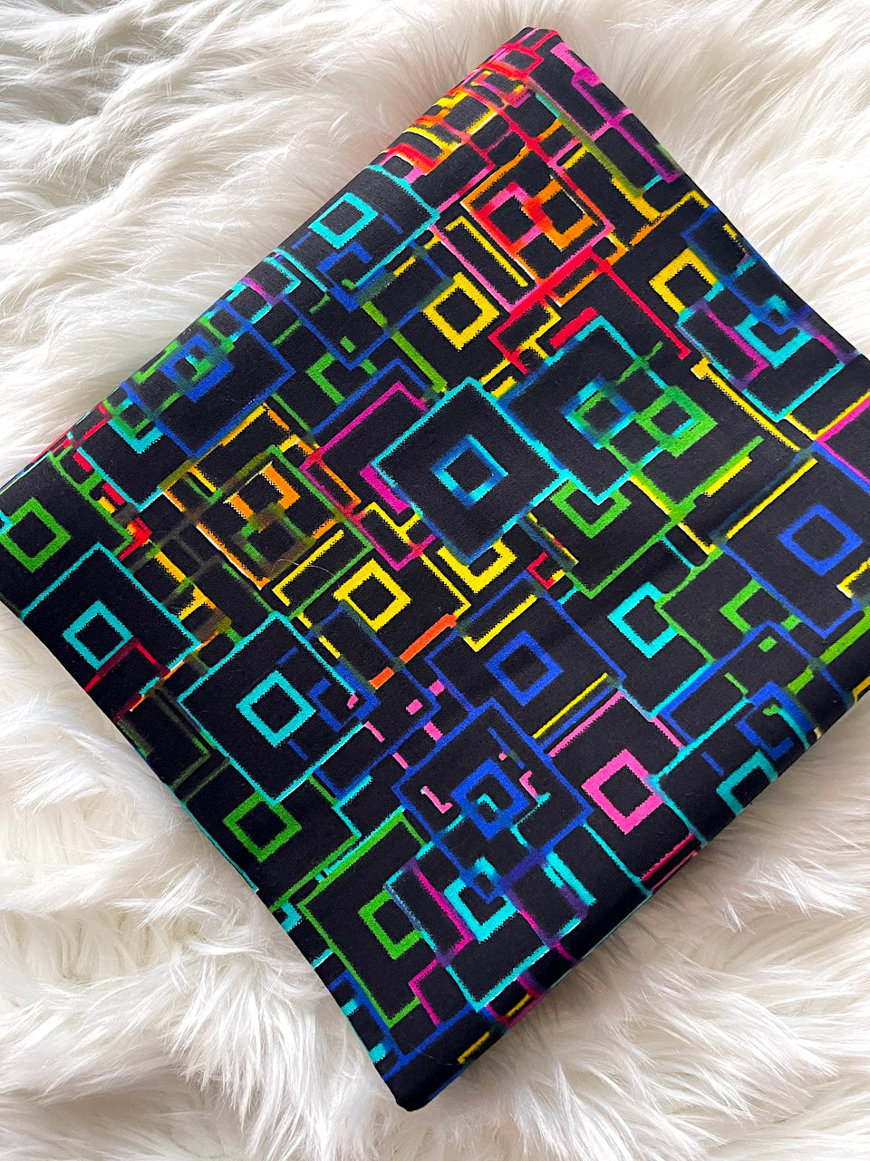 Colorful geometric patterned notebook on a white fluffy surface