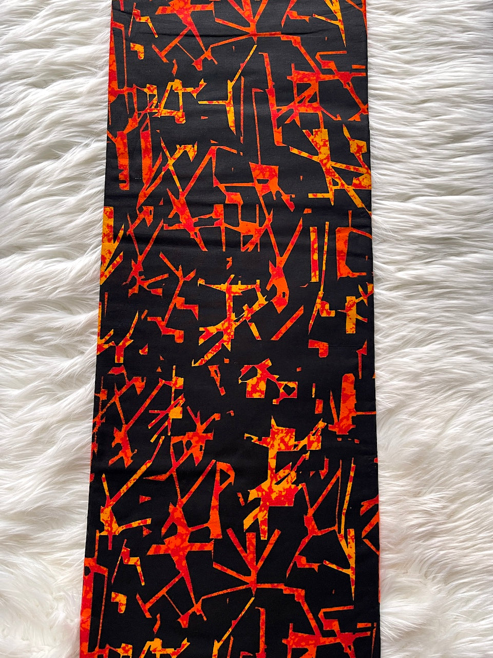 Black tie with orange abstract pattern on a white fur background