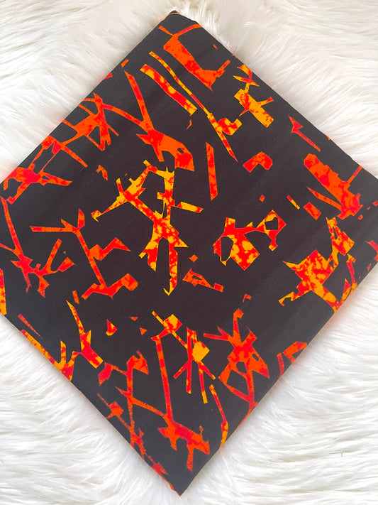 Black fabric with red and orange abstract pattern on a white textured background