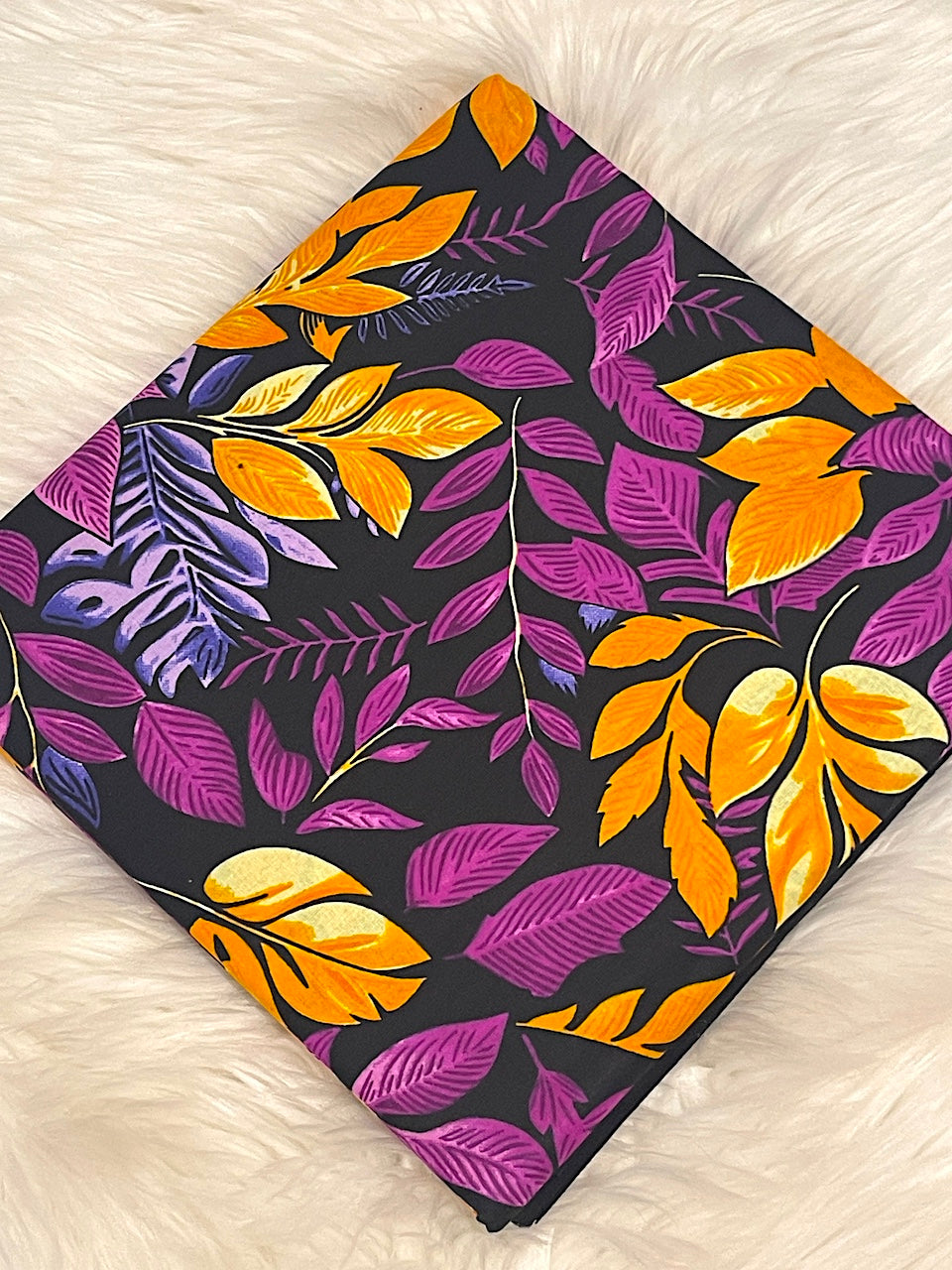Fabric with purple and orange leaf pattern on a white surface