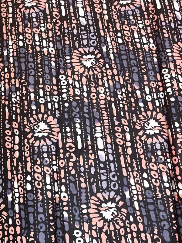 Close-up of a patterned fabric with pink and blue shapes on a black background