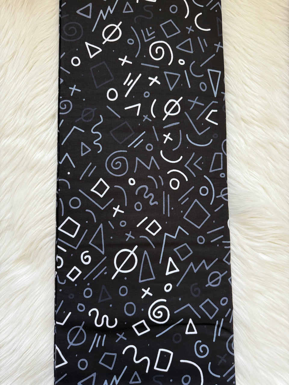 Black necktie with white geometric pattern on a textured white background
