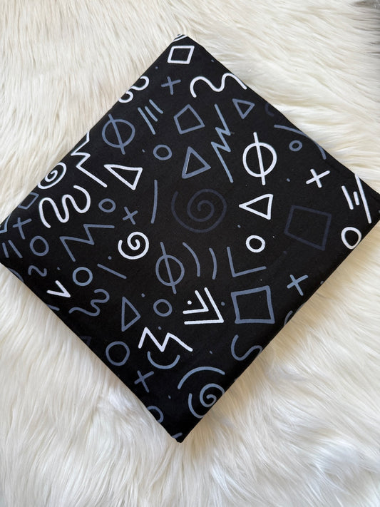 Black fabric with white geometric patterns on a white fluffy surface