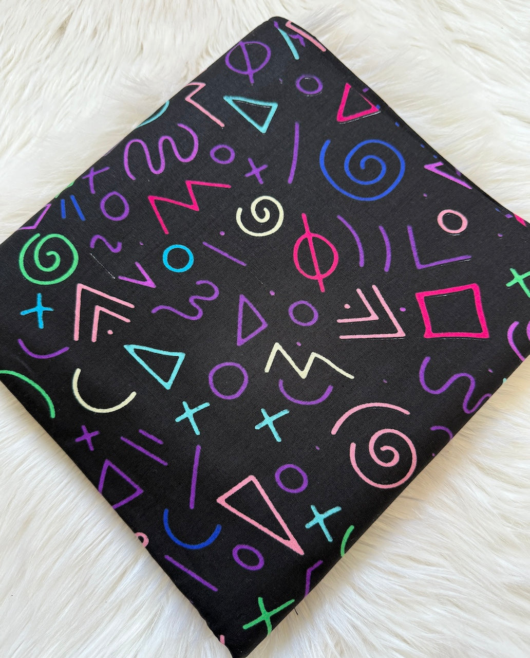 Black notebook with colorful geometric patterns on a white textured surface