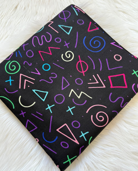Black notebook with colorful geometric patterns on a white textured surface