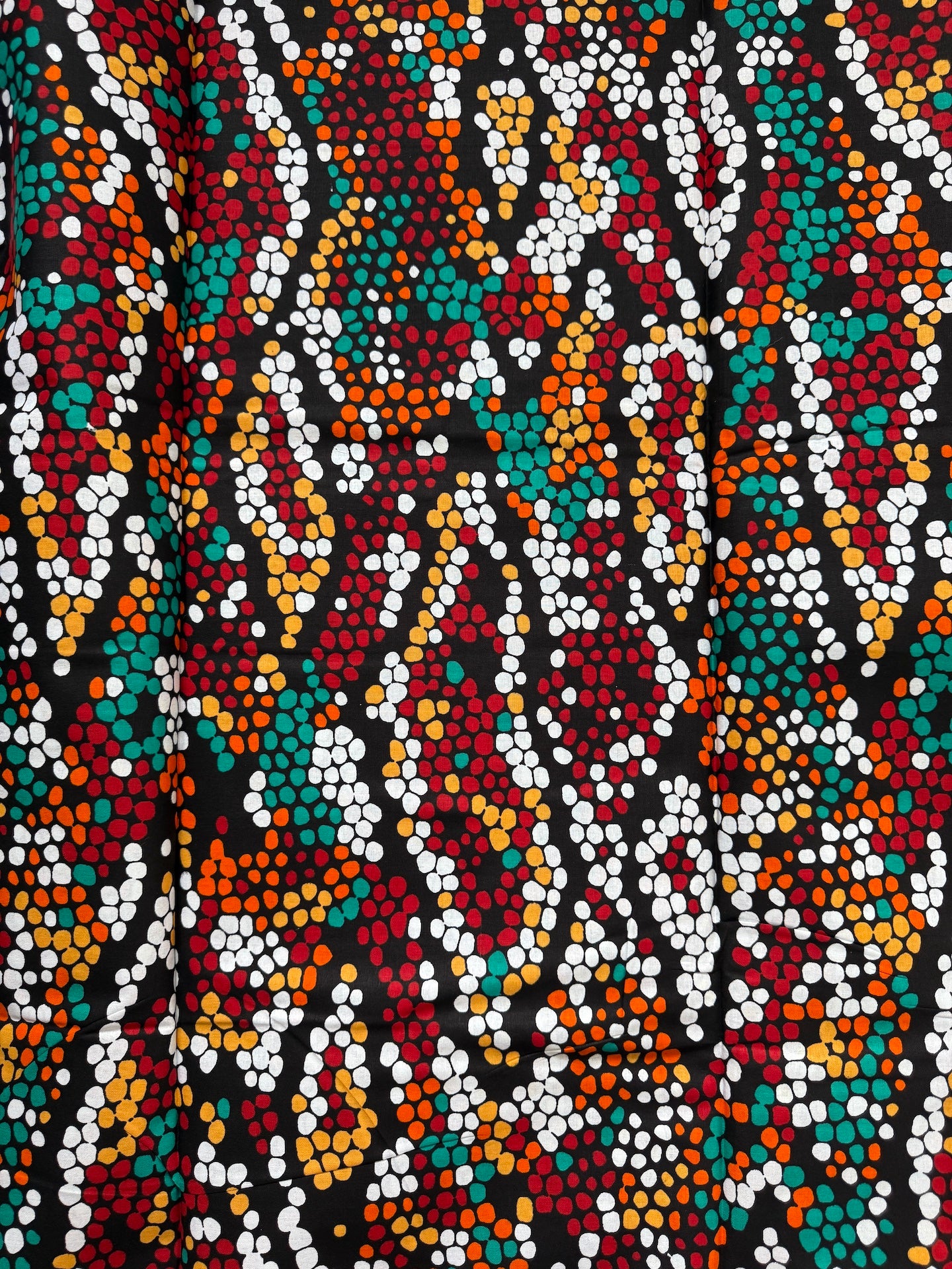 Close-up of a colorful patterned fabric with multicolor dots on a black background
