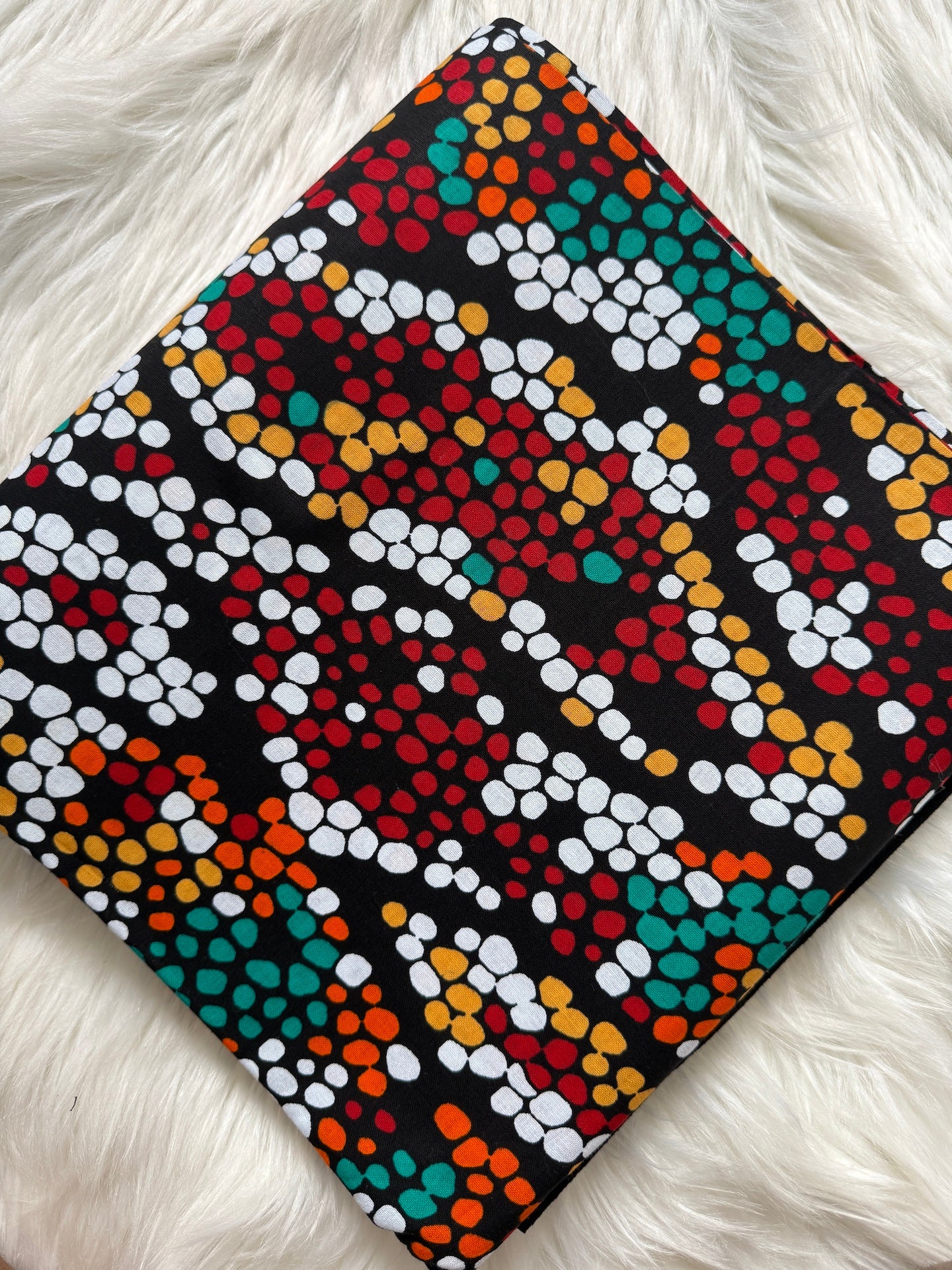 Colorful dot patterned notebook on a white fluffy surface