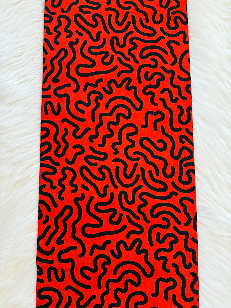 Red towel with black wavy pattern on a white textured background