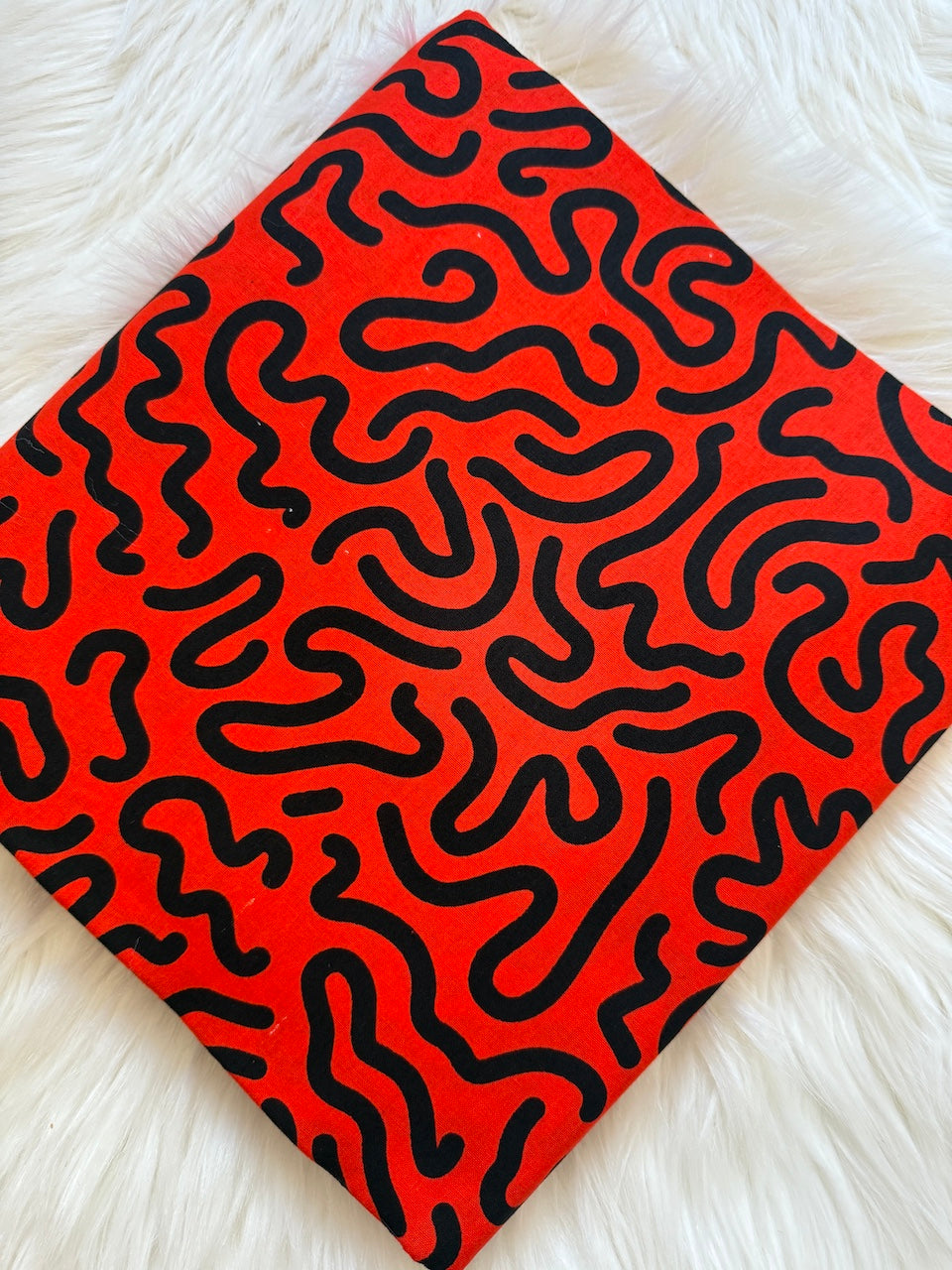 Red notebook with black wavy pattern on a white textured surface