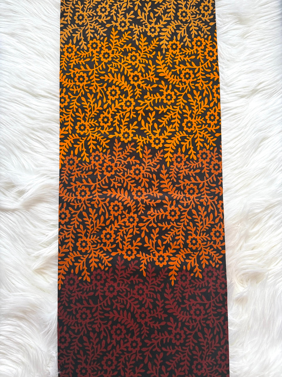 Yoga mat with orange and black floral pattern on a white fluffy surface