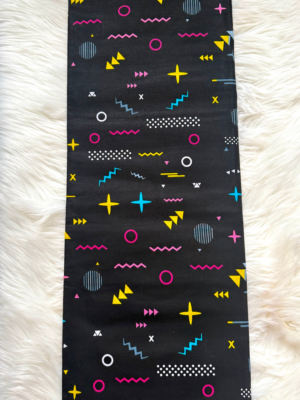 Black fabric with colorful geometric pattern on a white fluffy surface