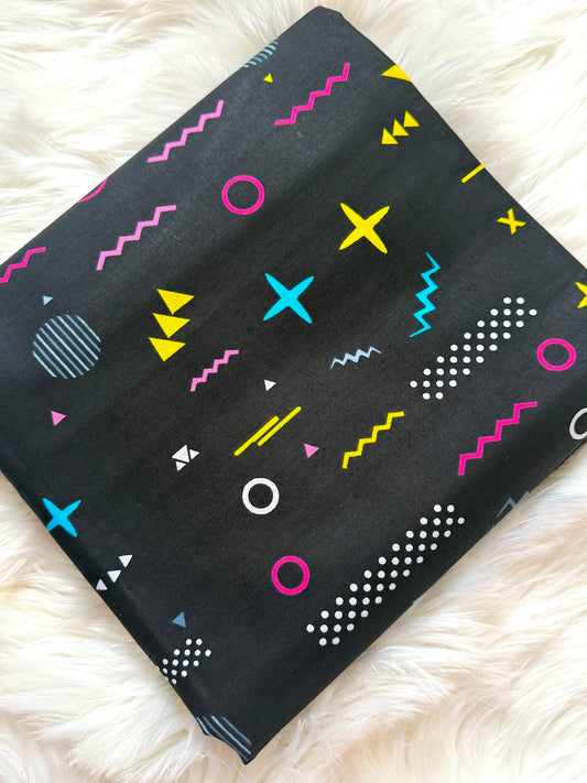Black fabric with colorful geometric patterns on a white fluffy surface
