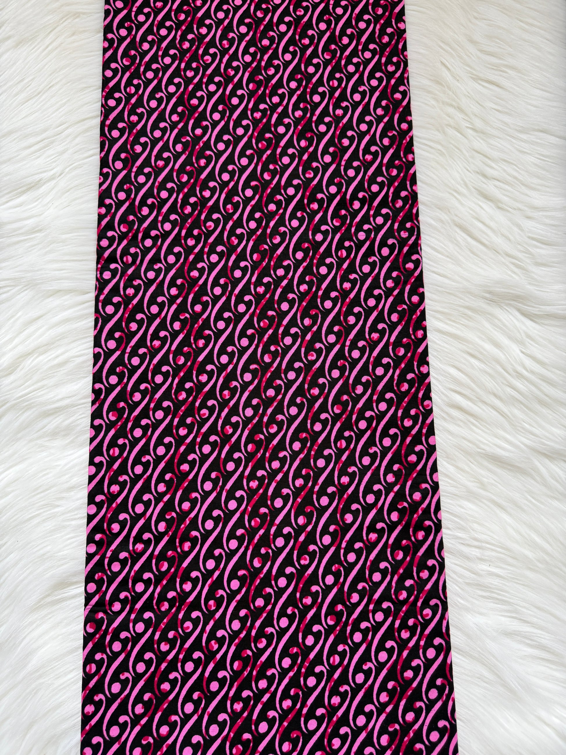 Pink and black patterned fabric on a white fur background