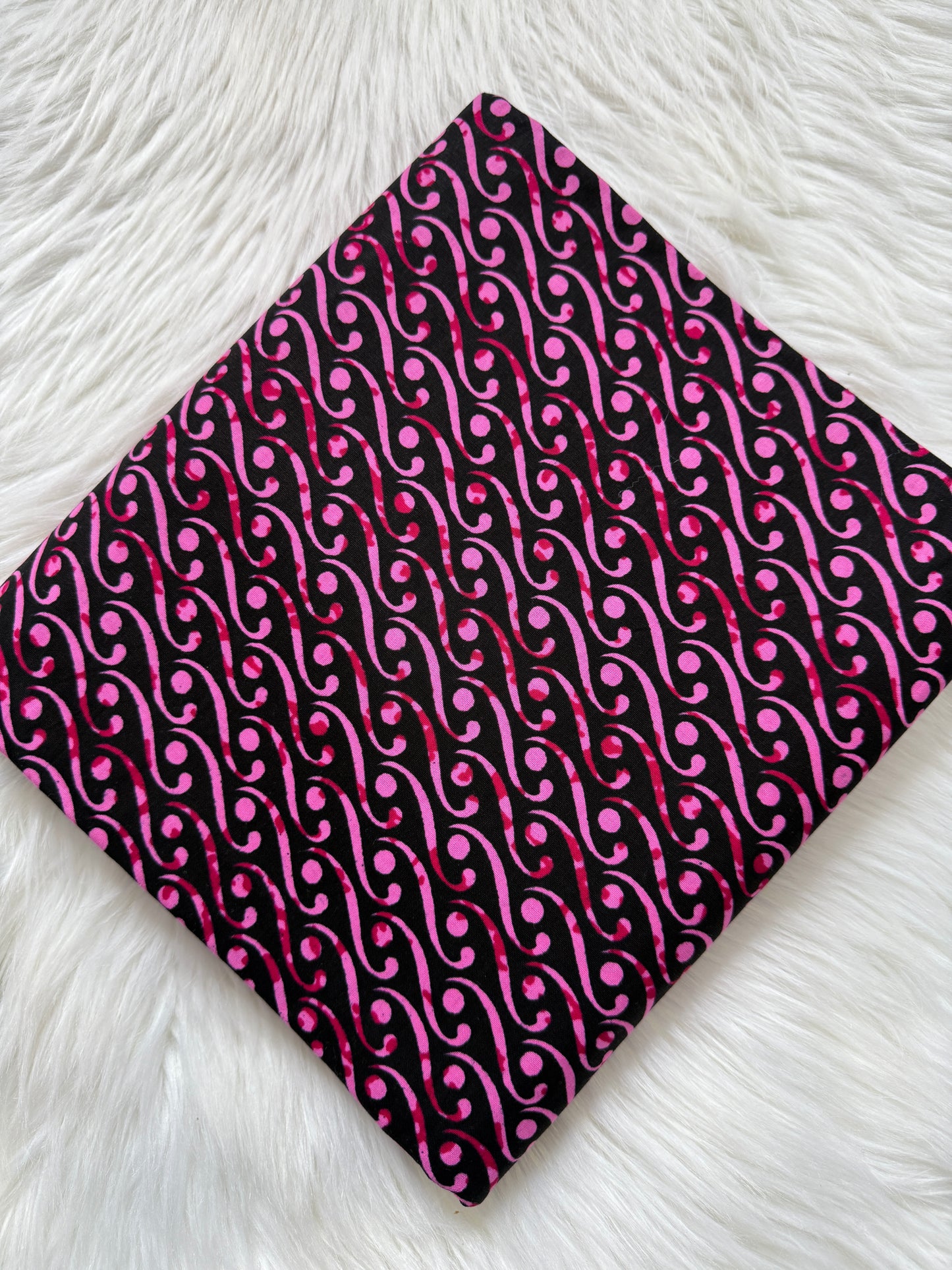 Fabric with pink and black pattern on a white textured surface