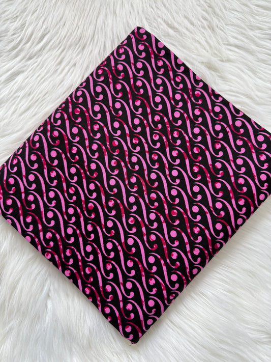 Fabric with pink and black pattern on a white textured surface